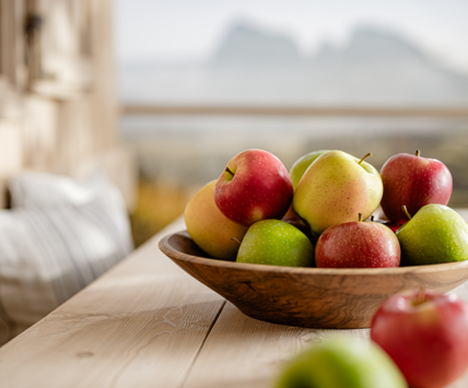 Ciotola di frutta con mele fresche assortite davanti a un paesaggio montano