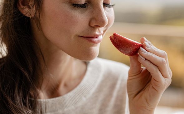 Donna avvicina il naso a una mela